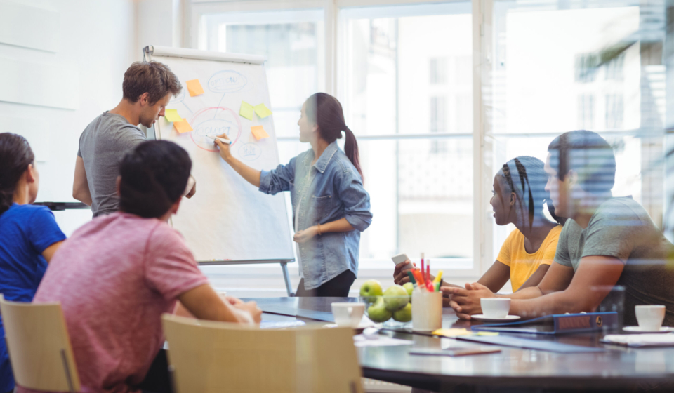 Business executives discussing with their colleagues on whiteboard during meeting at office